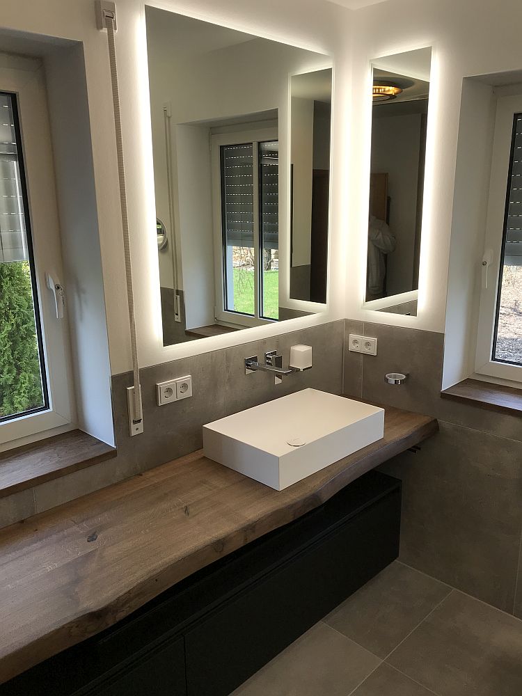 Helles Masterbad mit minimalistischem Design, einem eleganten Holz-Waschtisch, rechteckigem Waschbecken und Fenstern, die Tageslicht und Natur ins Bad bringen.