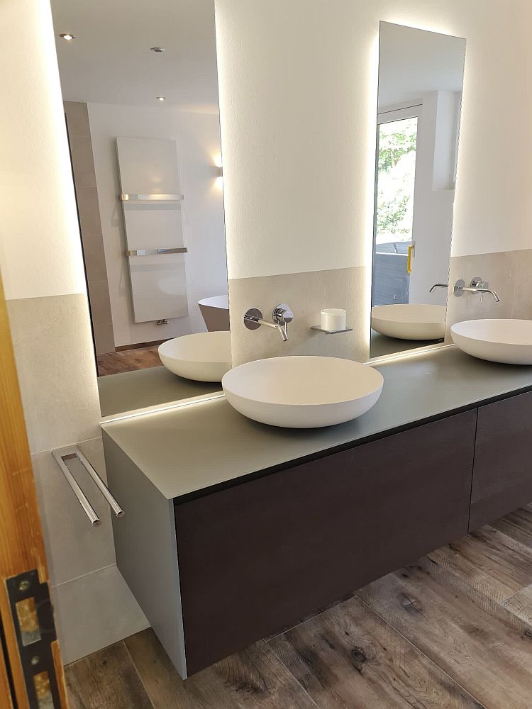 Ein modernes Badezimmer mit zwei weißen, runden Aufsatzwaschbecken auf einer dunklen Holzkonsole.