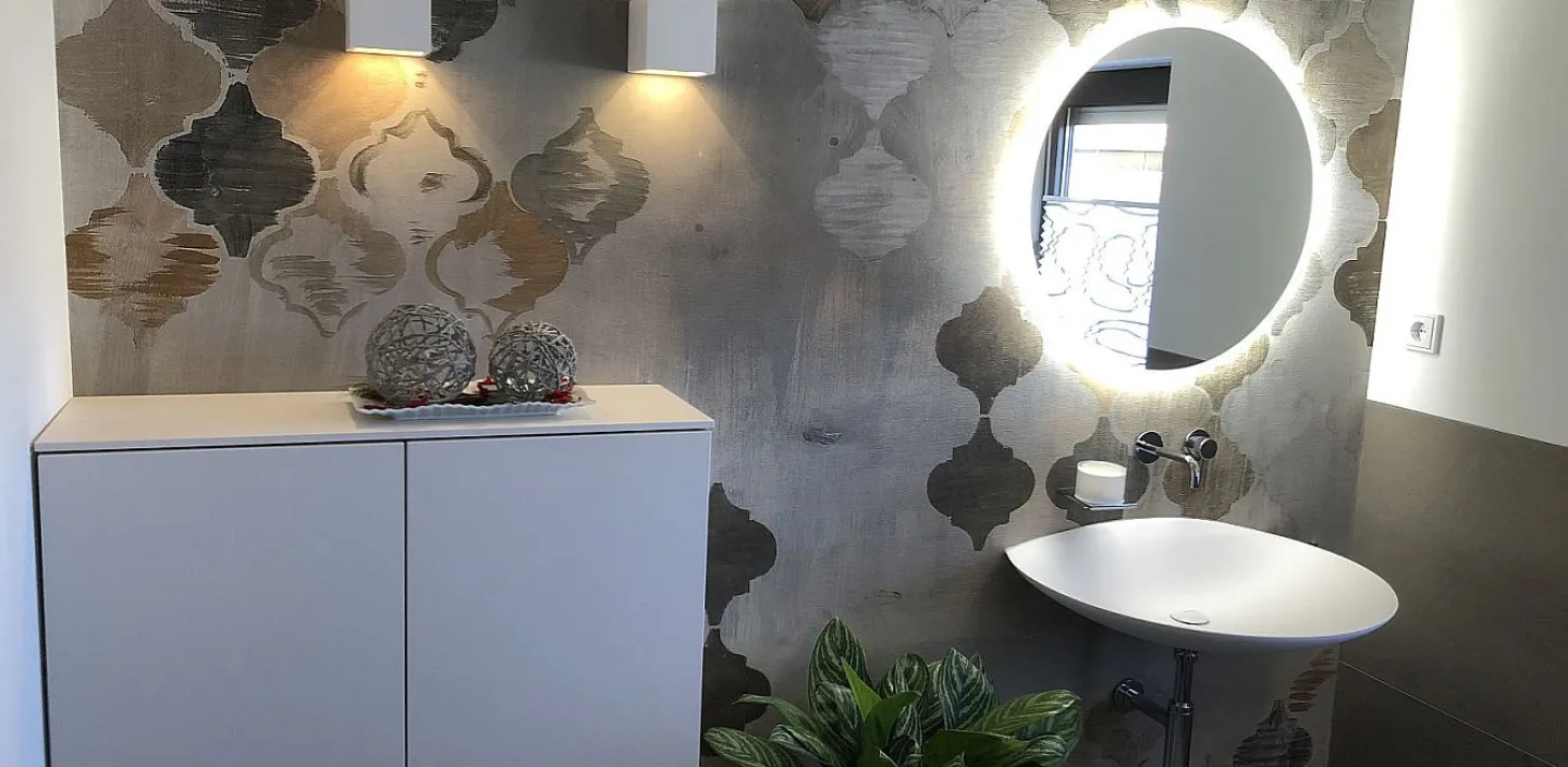 Ein stilvolles Gäste-WC mit einer dekorativen Wand in warmen Ornamentmustern und sanfter Beleuchtung. 