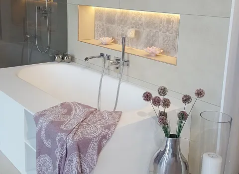  Das Bild zeigt eine moderne Badewanne mit integrierter Nische und indirekter Beleuchtung.