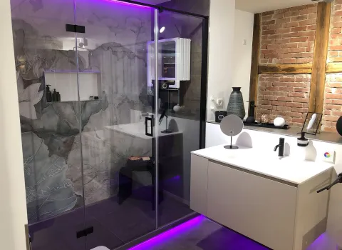 Ein modernes Badezimmer mit floraler Duschwand, sichtbarer Backsteinwand, stilvoller Beleuchtung und einem schwebenden Waschtisch.