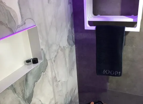 Eine stilvolle Badezimmerecke mit floraler Wandgestaltung, einem Handtuchhalter, einer beleuchteten Nische und einem Hocker.