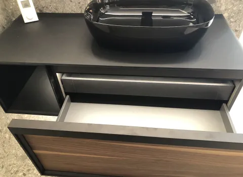 Ein moderner Waschtisch mit einer Schublade in Holzoptik und einem glänzenden schwarzen Aufsatzwaschbecken.