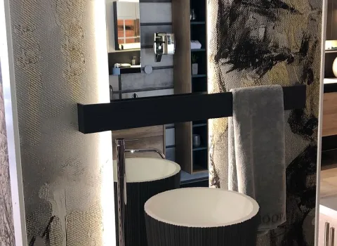 Ein eleganter Standwaschtisch mit schwarzem Reliefmuster, einem beleuchteten Spiegel mit abgerundeten Kanten und kunstvoller Wandgestaltung im Hintergrund.