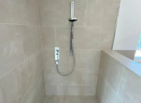Moderne Dusche mit Regendusche und hell-beigen Fliesen aus dem geplanten und realisierten Badezimmer in Schweinfurt vom Sanitär- und Heizungshandwerksunternehmen smr GmbH.