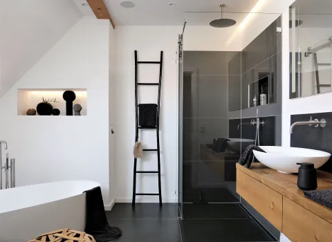 Referenzbad Niederwerrn mit barrierefreier Dusche, Massivholzwaschtisch und freistehender Badewanne.