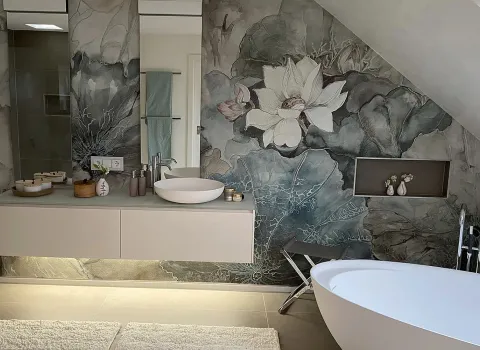 Ein elegantes Dachbadezimmer mit einer freistehenden weißen Badewanne und einem Waschtisch, der mit zwei runden Waschbecken und indirekter Beleuchtung gestaltet ist. 