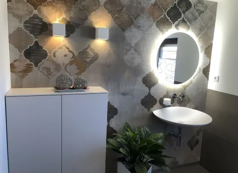 Ein stilvolles Gäste-WC mit einer dekorativen Wand in warmen Ornamentmustern und sanfter Beleuchtung. 