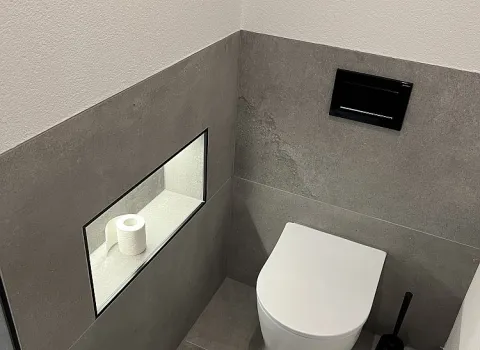Wandhängendes WC mit beleuchteter Wandnische.