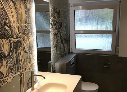 Gedimmtes Badezimmerambiente mit Blick auf das Fenster.