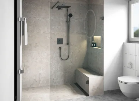 Eine luxuriöse Walk-In-Dusche mit großformatigen beigen Natursteinfliesen zeigt eine integrierte Sitzbank und eine elegante Nischenablage mit Pflegeprodukten.