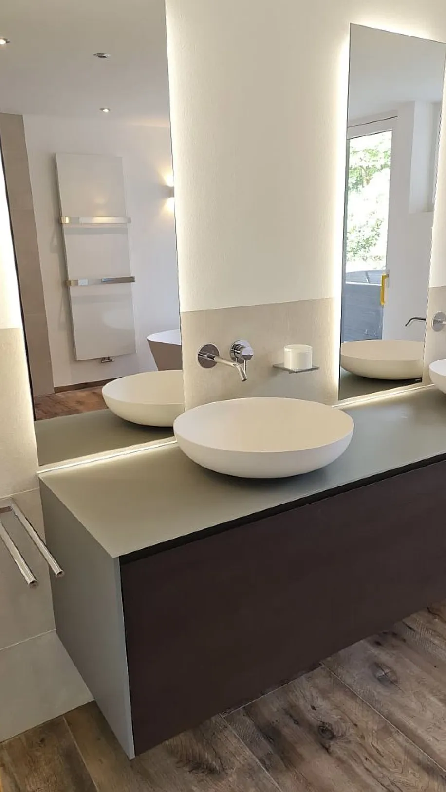 Ein modernes Badezimmer mit zwei weißen, runden Aufsatzwaschbecken auf einer dunklen Holzkonsole.