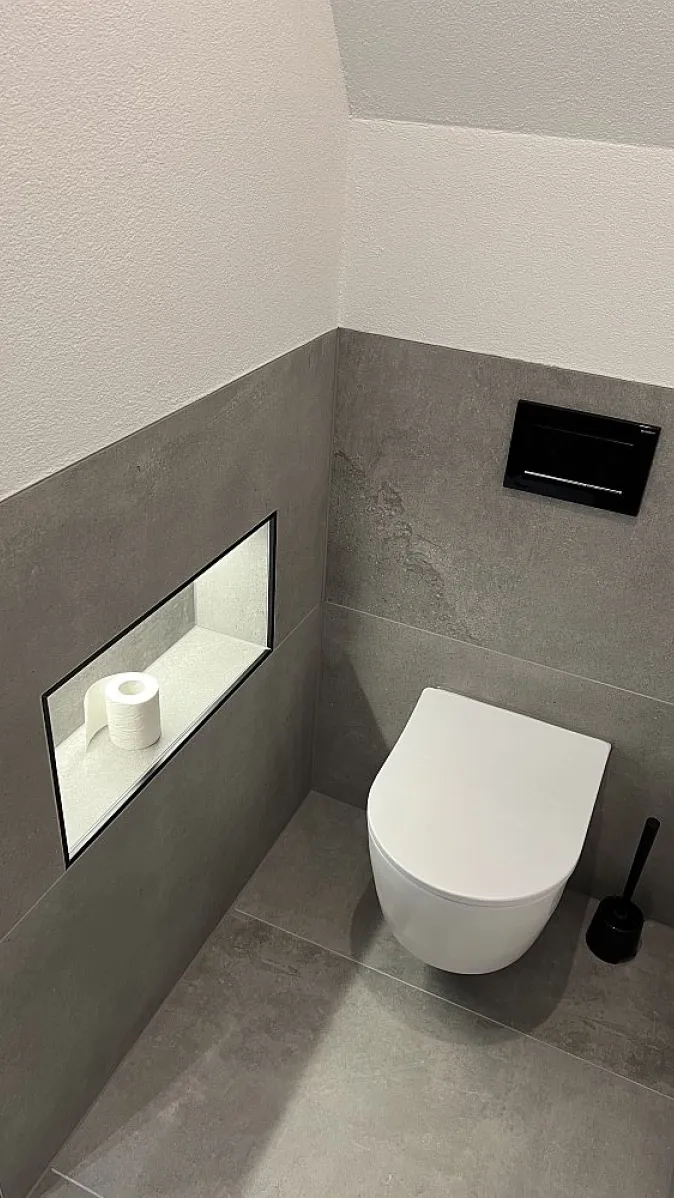 Wandhängendes WC mit beleuchteter Wandnische.