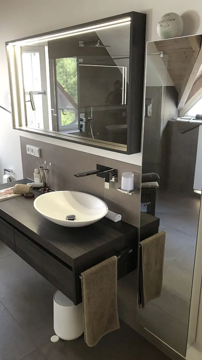 Waschtisch mit Wandarmatur, großer Spiegel mit LED-Rahmen und modernen Details. Ein bodenlanger Spiegel erweitert optisch den Raum.