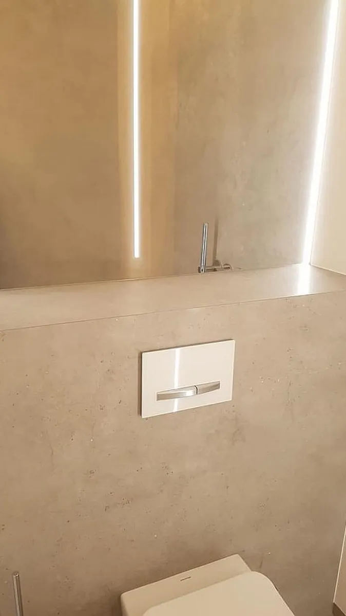 Minimalistisches WC-Design mit indirekter LED-Beleuchtung, die ein goldenes Lichtszenario schafft.