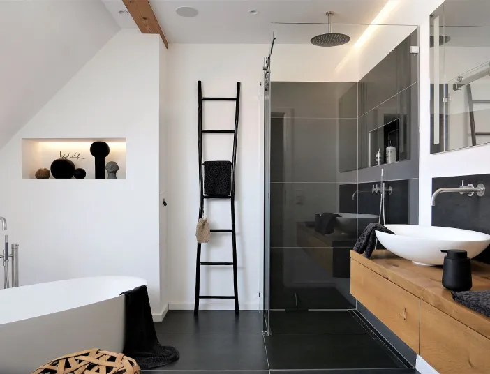 Referenzbad Niederwerrn mit barrierefreier Dusche, Massivholzwaschtisch und freistehender Badewanne.